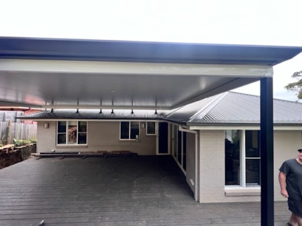 A Man Standing in Front of a House With a Carport — Outdoor Leisure Living In Tuggerah, NSW