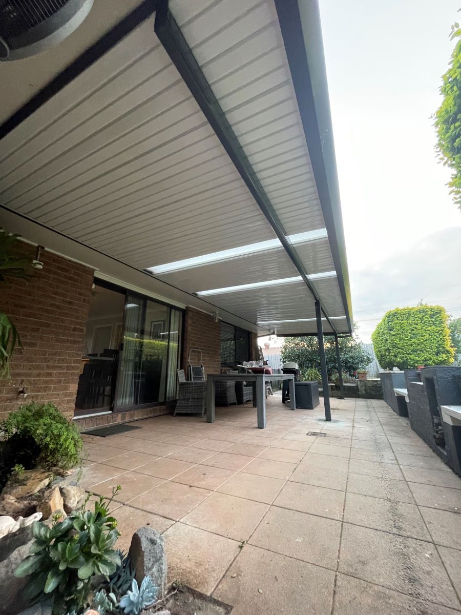 A Large Covered Patio With a Table and Chairs Under a Roof — Outdoor Leisure Living In Woy Woy, NSW