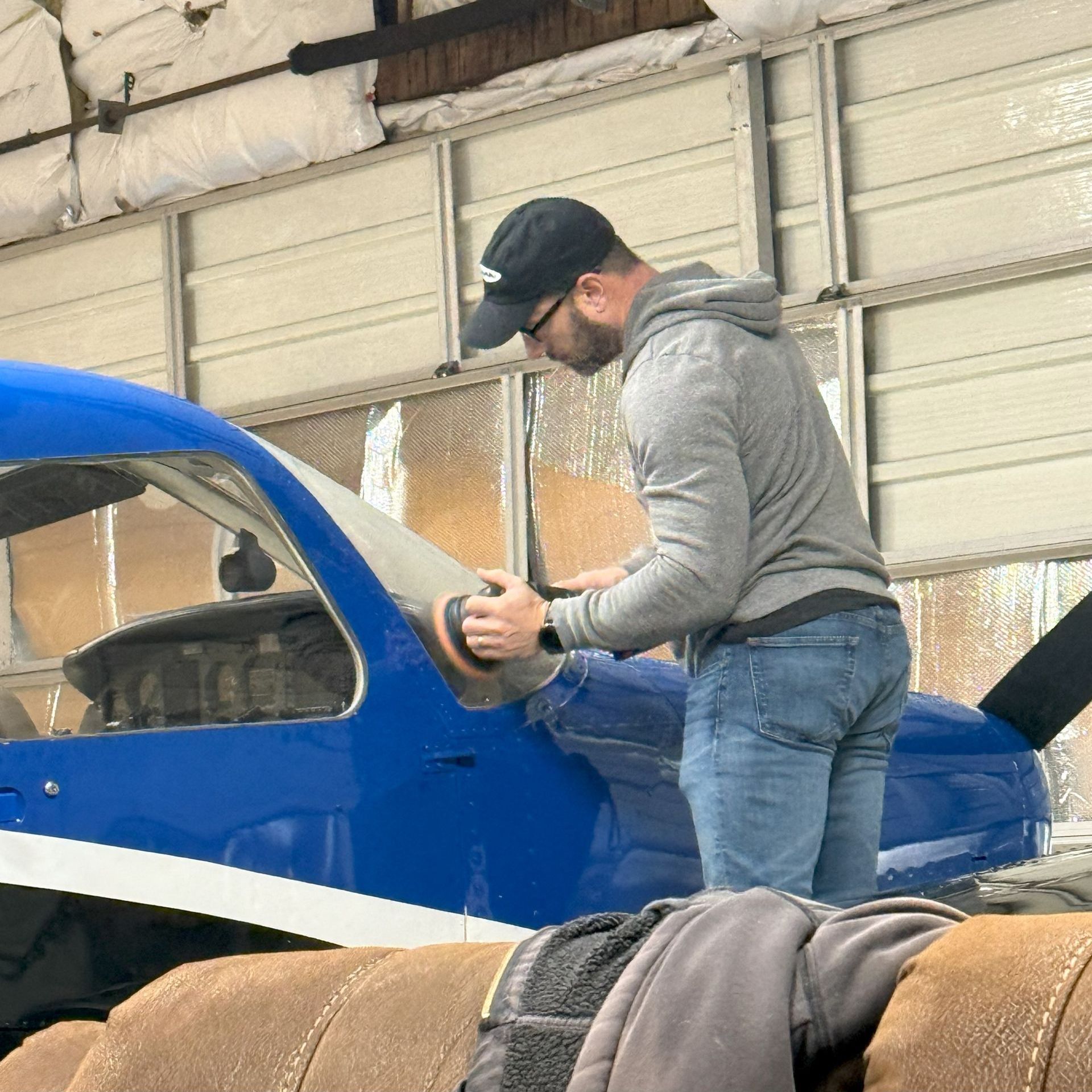 A man is working on a blue airplane in a hangar