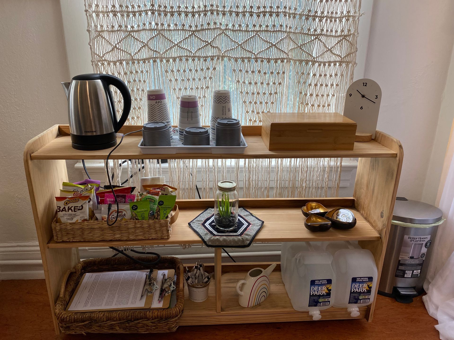 A wooden shelf with a kettle and cups on it.
