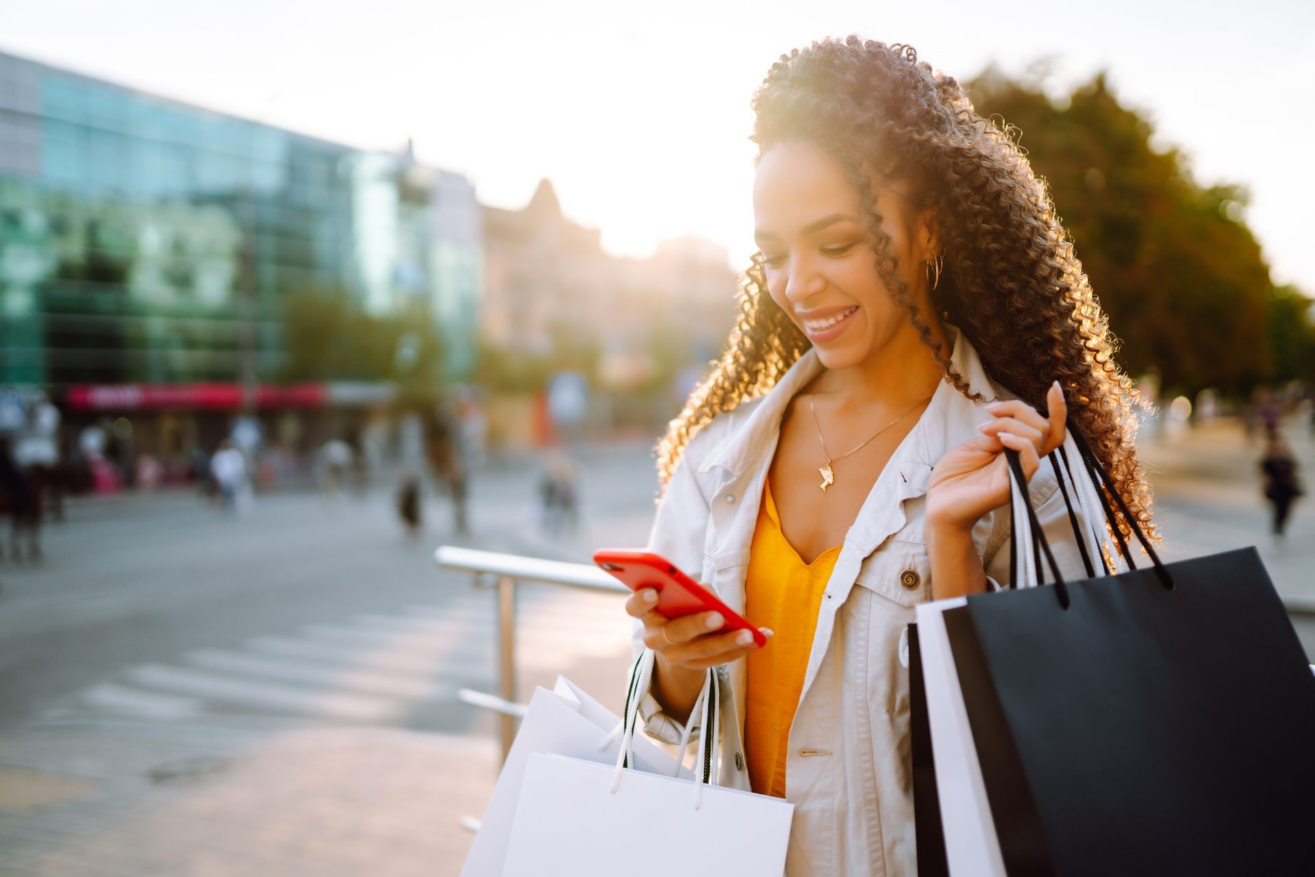Woman holding shopping bags and looking at phone in hand. 