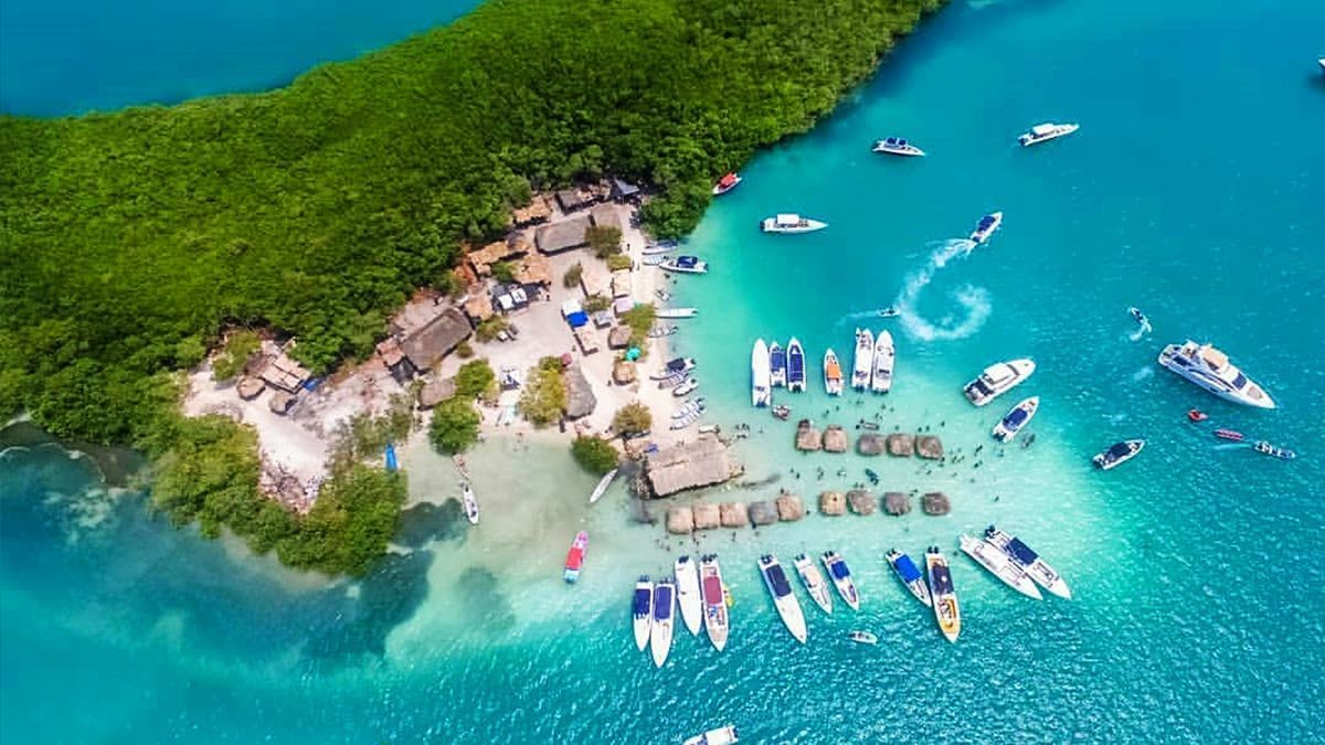Isla con barcos en aguas turquesas y exuberante follaje verde  | Mevak Agency