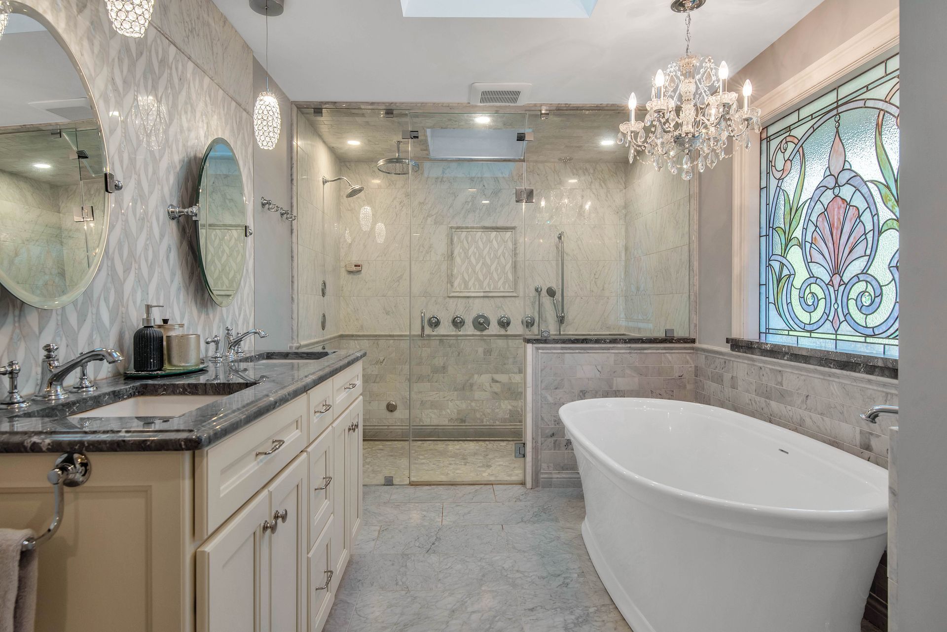 Elegant bathroom with dual sinks, walk-in shower, and freestanding tub. Stained glass window.