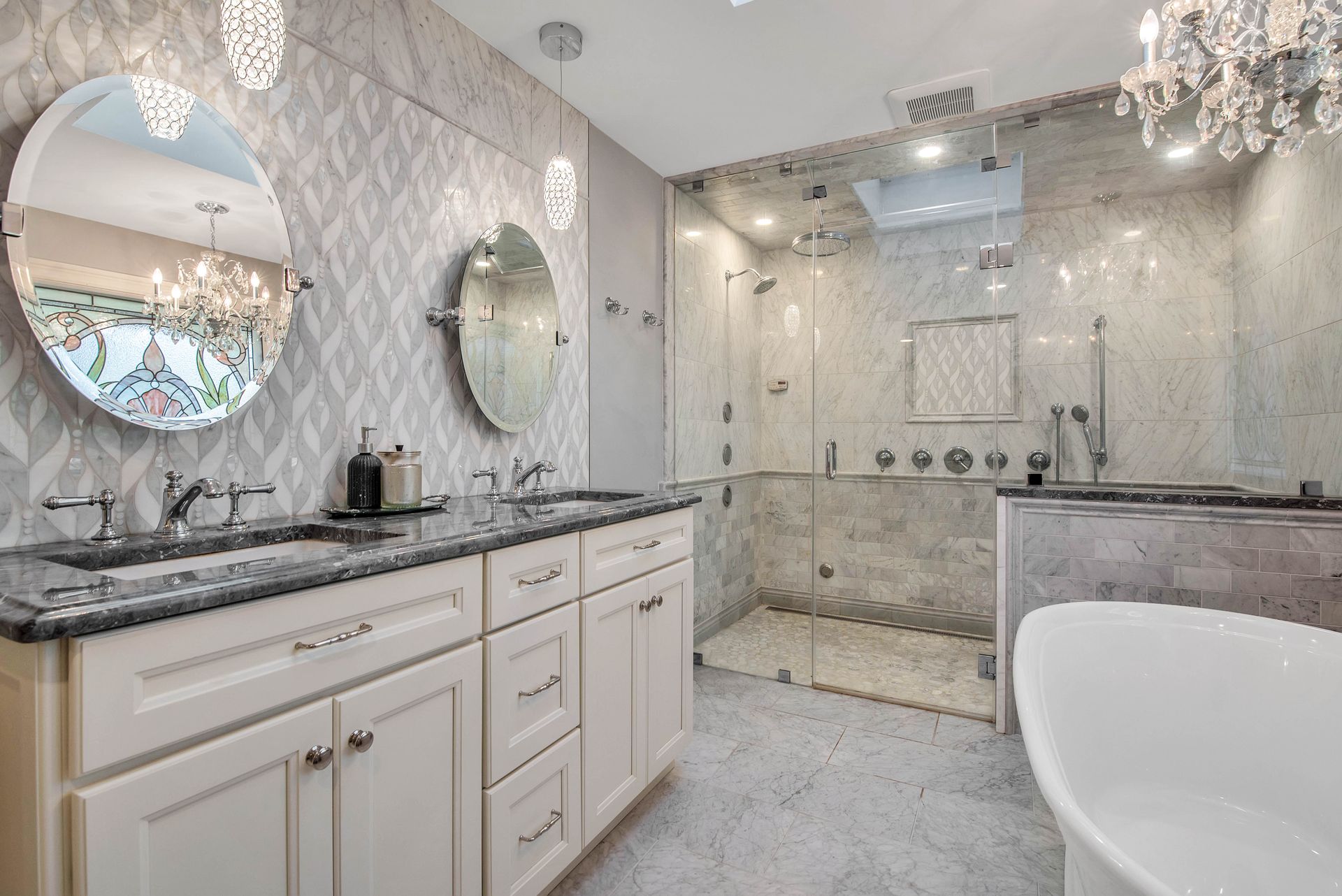 Luxurious bathroom with double vanity, walk-in shower, and freestanding tub. Gray and white tones.