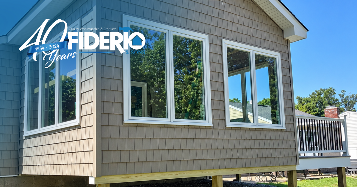 White-sided cabin exterior with large windows and a deck, under a blue sky