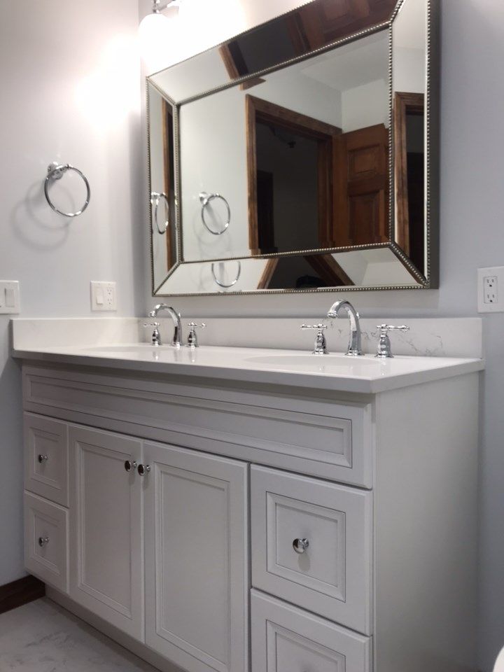 White bathroom vanity with double sinks and large mirror.