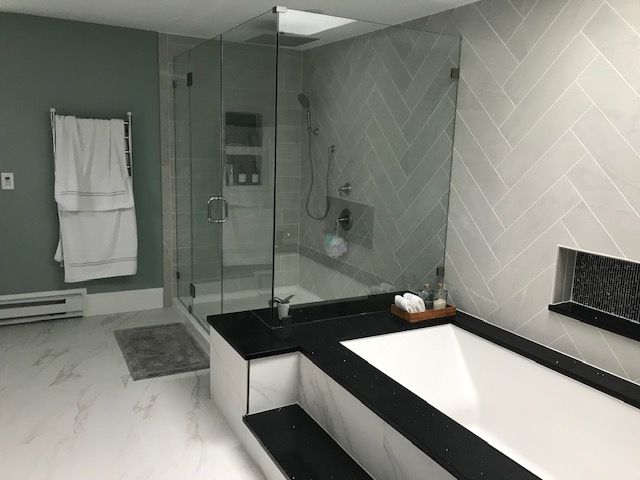 Modern bathroom with glass shower, bathtub, and green and gray walls.