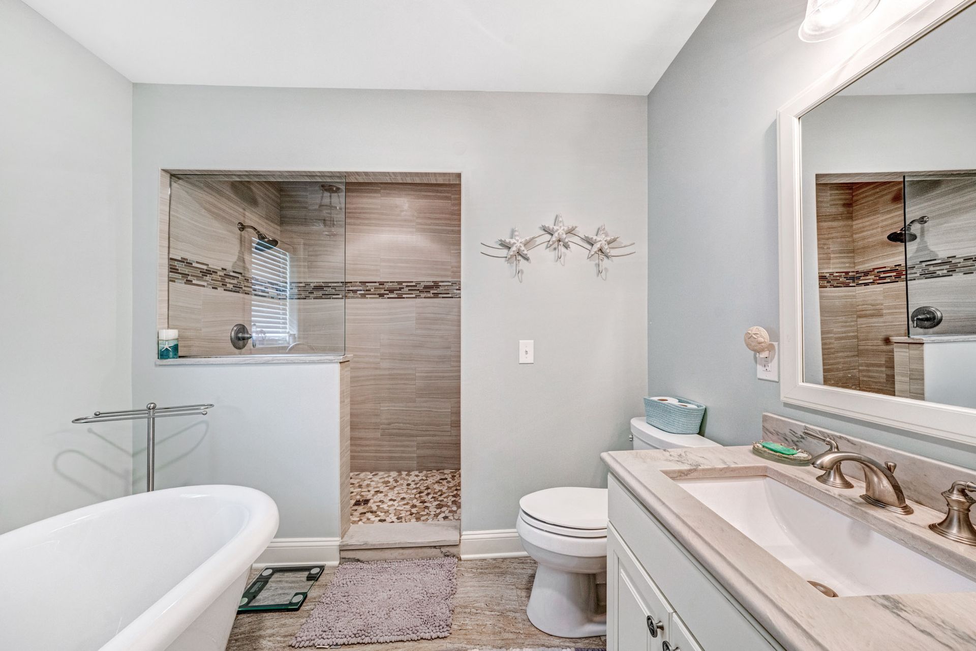 Bathroom with a soaking tub, walk-in shower, toilet, vanity, and light blue walls.