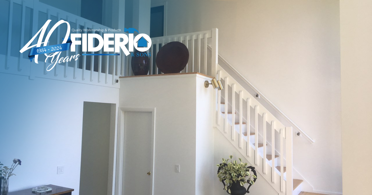 White staircase with railing in a bright room, above a small white structure and a vase of flowers.