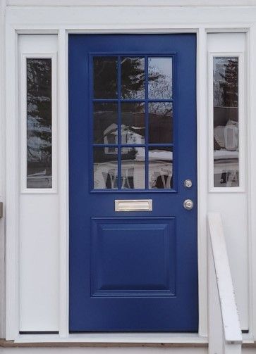 Blue front door with sidelights, white trim, and a mailbox.