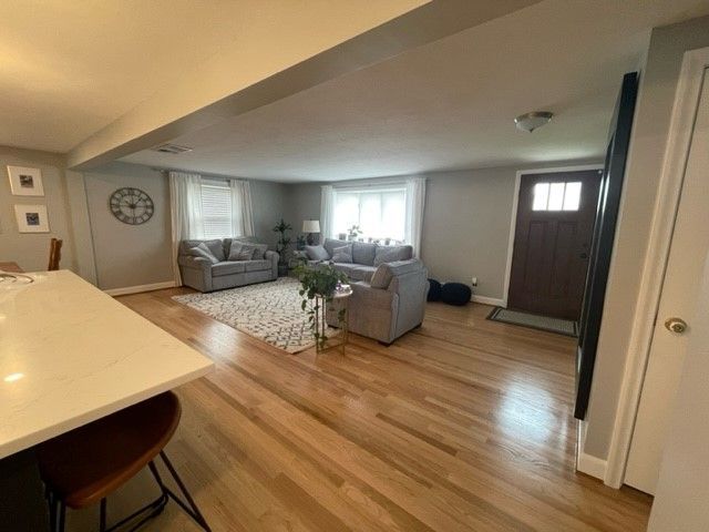 Open-concept living space with gray couches, wooden floors, and a white countertop.