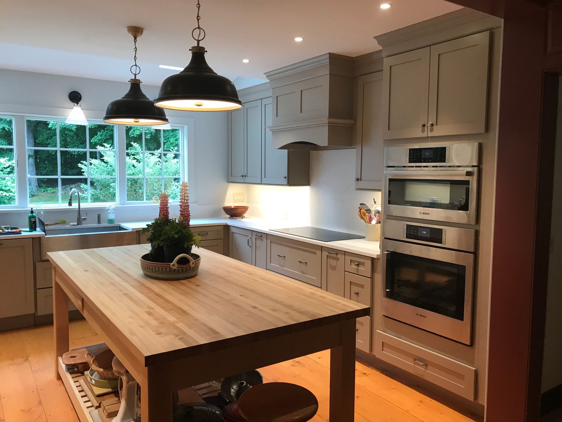 A modern kitchen with a wooden island, light cabinets, and stainless steel appliances.
