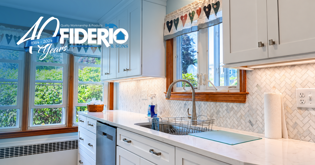 Bright white kitchen with blue accents, bay window, and heart decorations above the sink