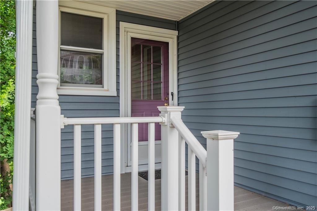 Porch with white railings, a blue-grey exterior, and a purple door.