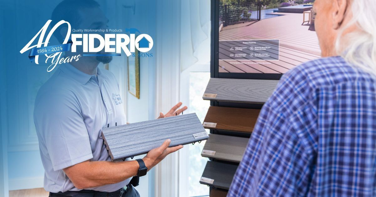Person holding a keyboard beside a monitor showing a home exterior and Federico Homes logo