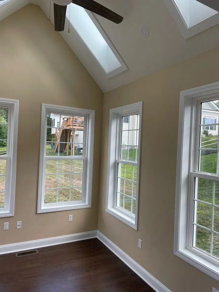 Interior room with angled ceiling, skylights, and windows, cream walls, dark wood floor.