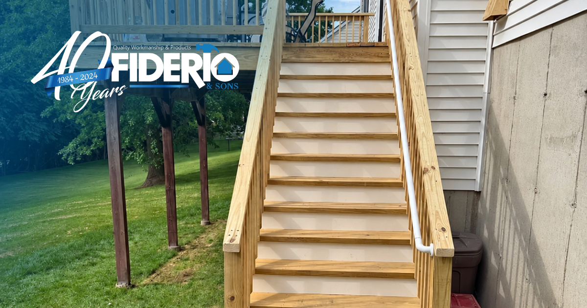 Wooden outdoor staircase with handrails beside a house and grassy yard