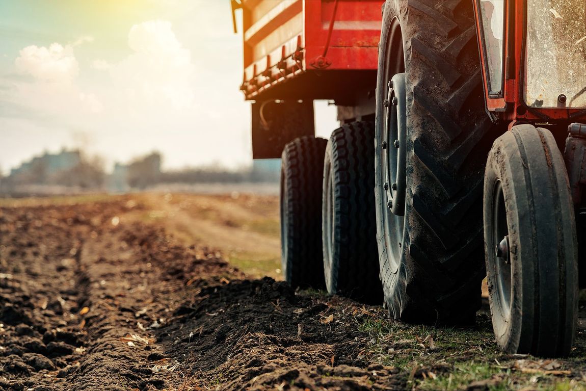 A tractor is plowing a field with a trailer attached to it.