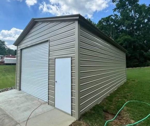 A tan metal garage with a white roll-up door and a small side-entry door, situated on a concrete slab in a grassy yard.