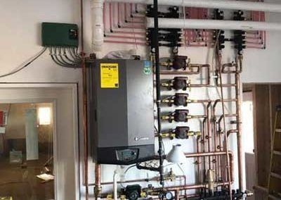 Heating system with pipes and pumps on a wall, near a door.