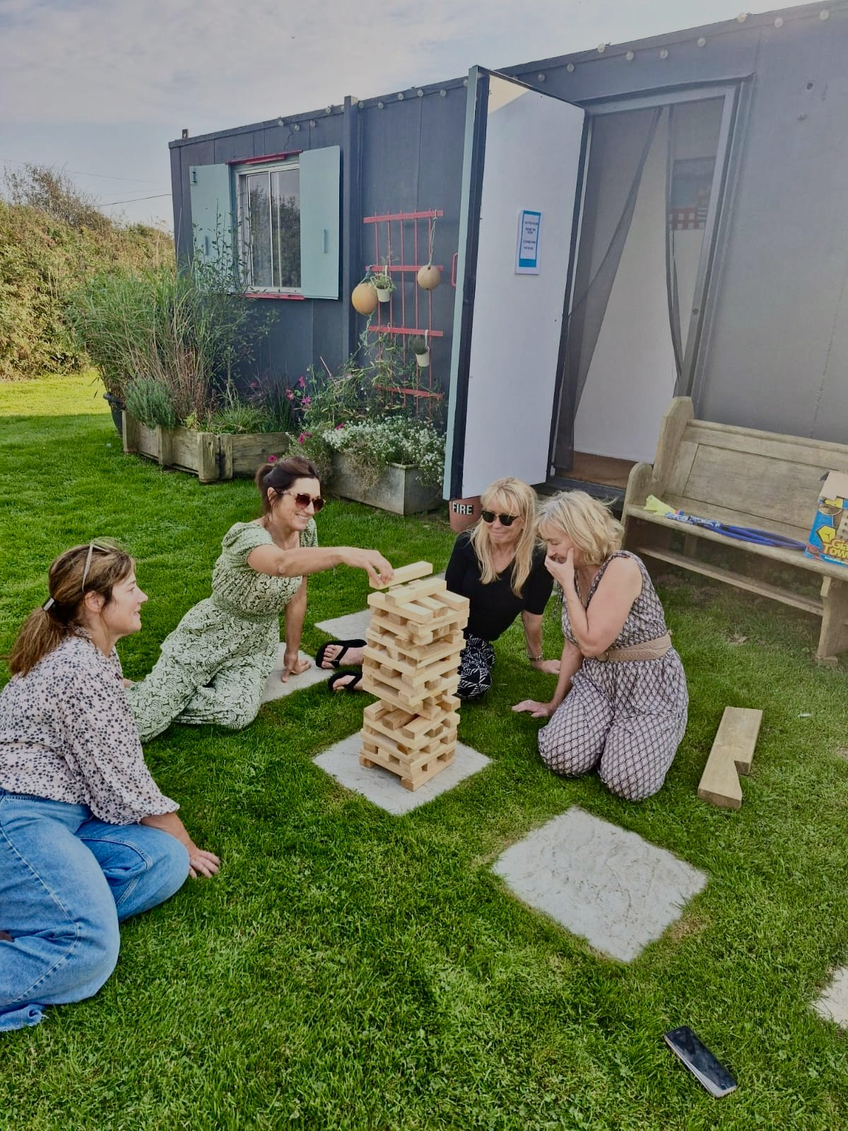 Group of women playing lawn games outside their safari tents during a fun group glamping stay in Cornwall
