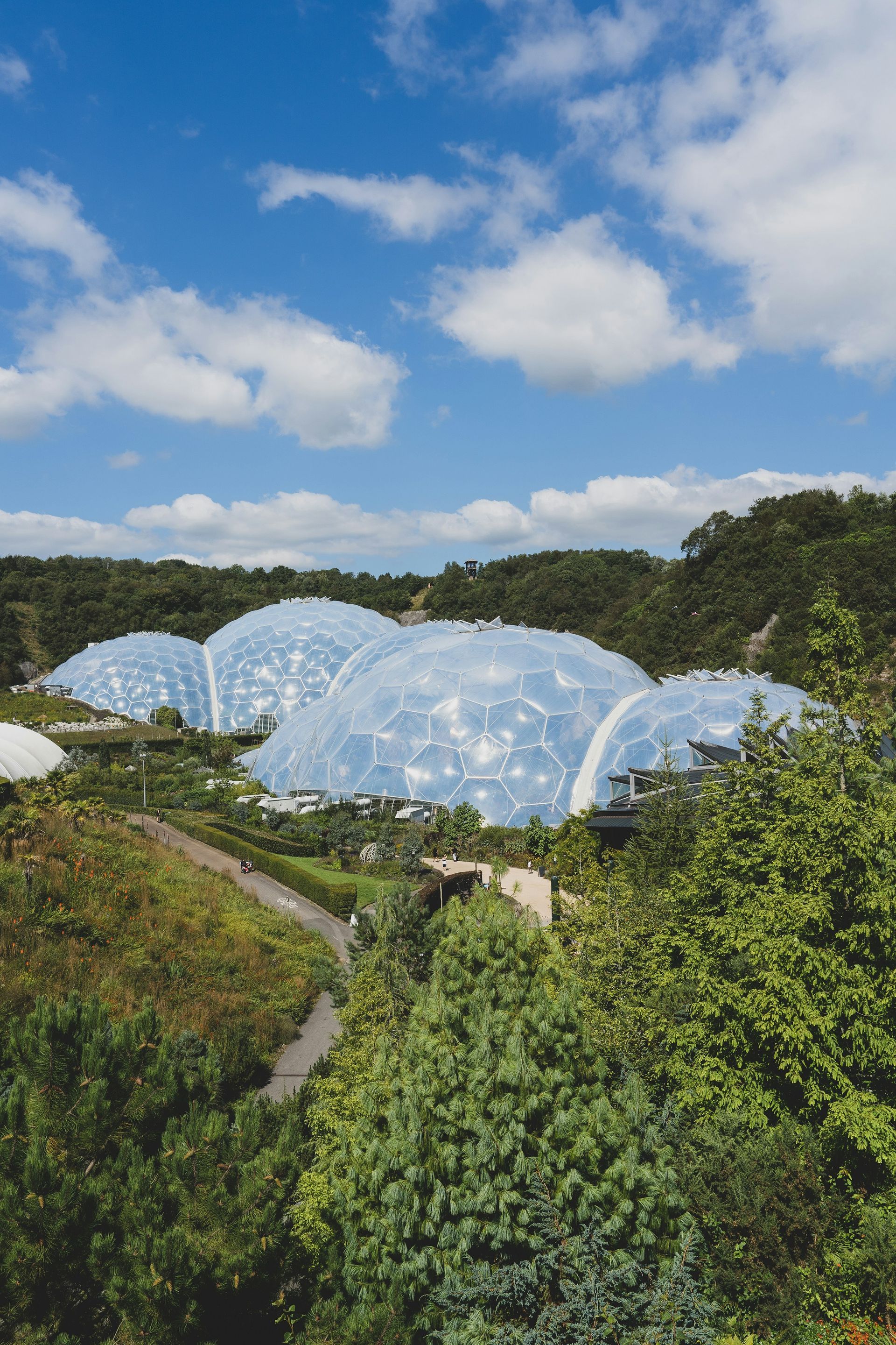 Giant geodesic domes nestled in a lush green landscape under a blue sky with clouds.