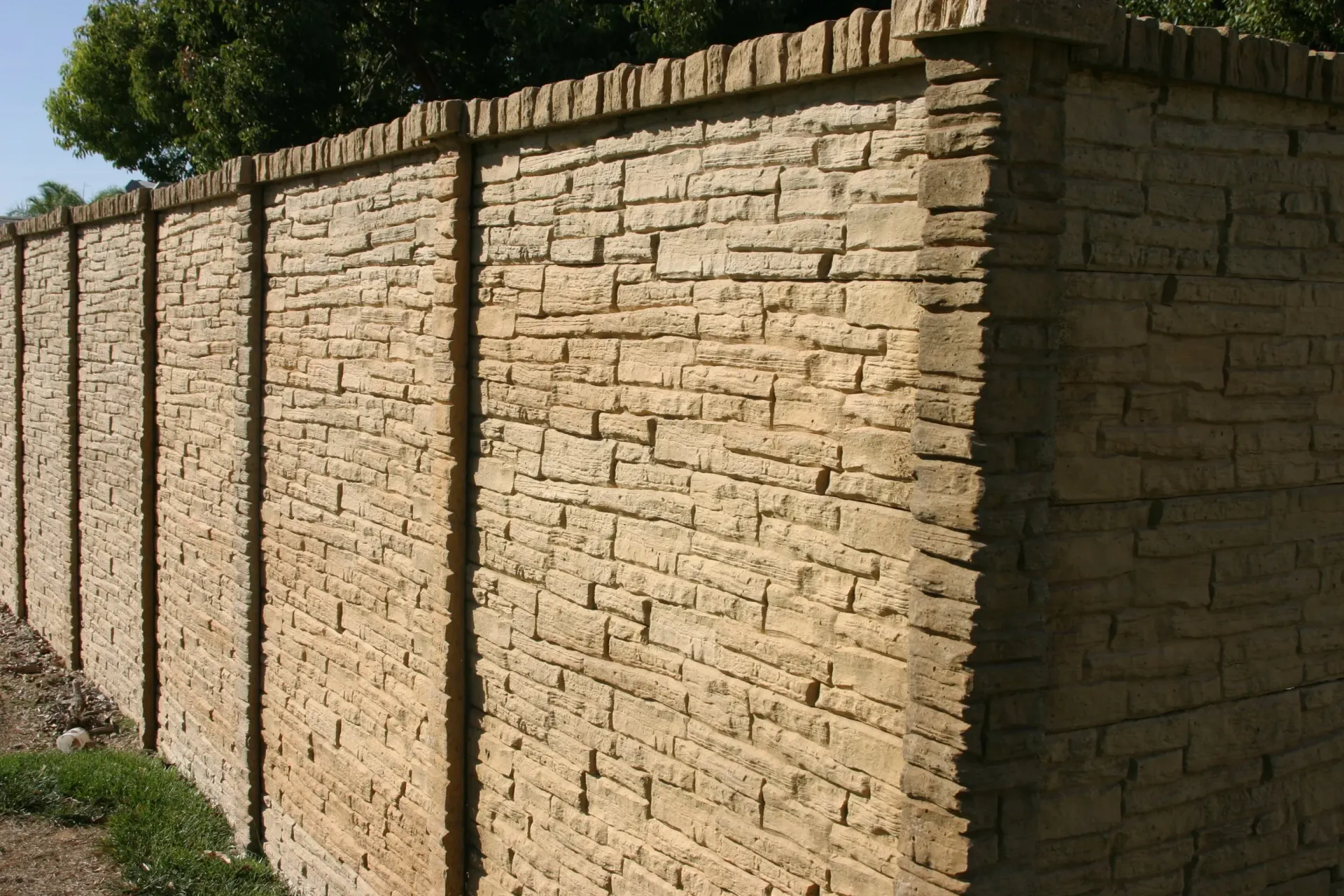 Stack of vertical slat replacement fence panels in a residential backyard, prepared for installation.