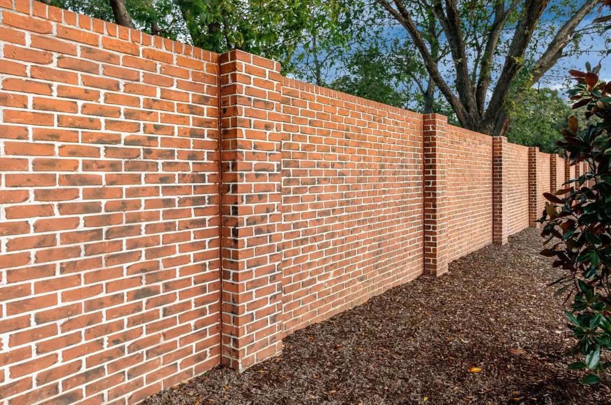 Stack of vertical slat replacement fence panels in a residential backyard, prepared for installation.