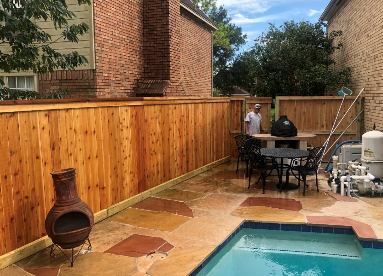 Stack of vertical slat replacement fence panels in a residential backyard, prepared for installation.