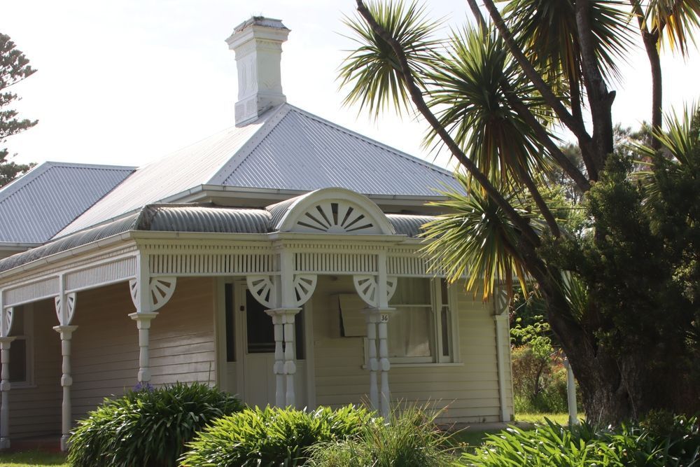 A White House With a Porch and Palm Trees in Front of It — Monty's Metal Roofing In Pottsville, NSW
