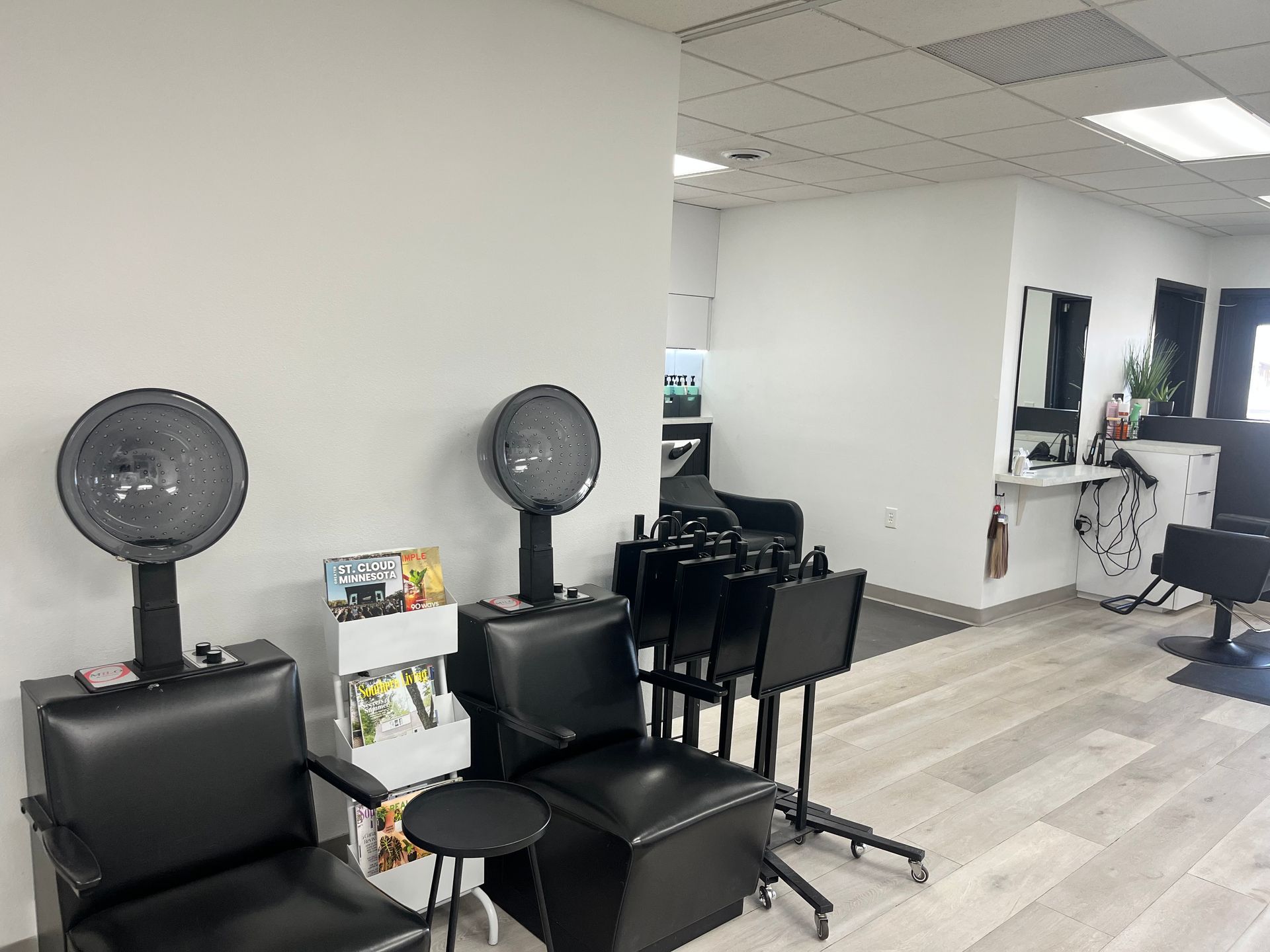 Modern salon waiting area with black styling chairs, fans, and white walls