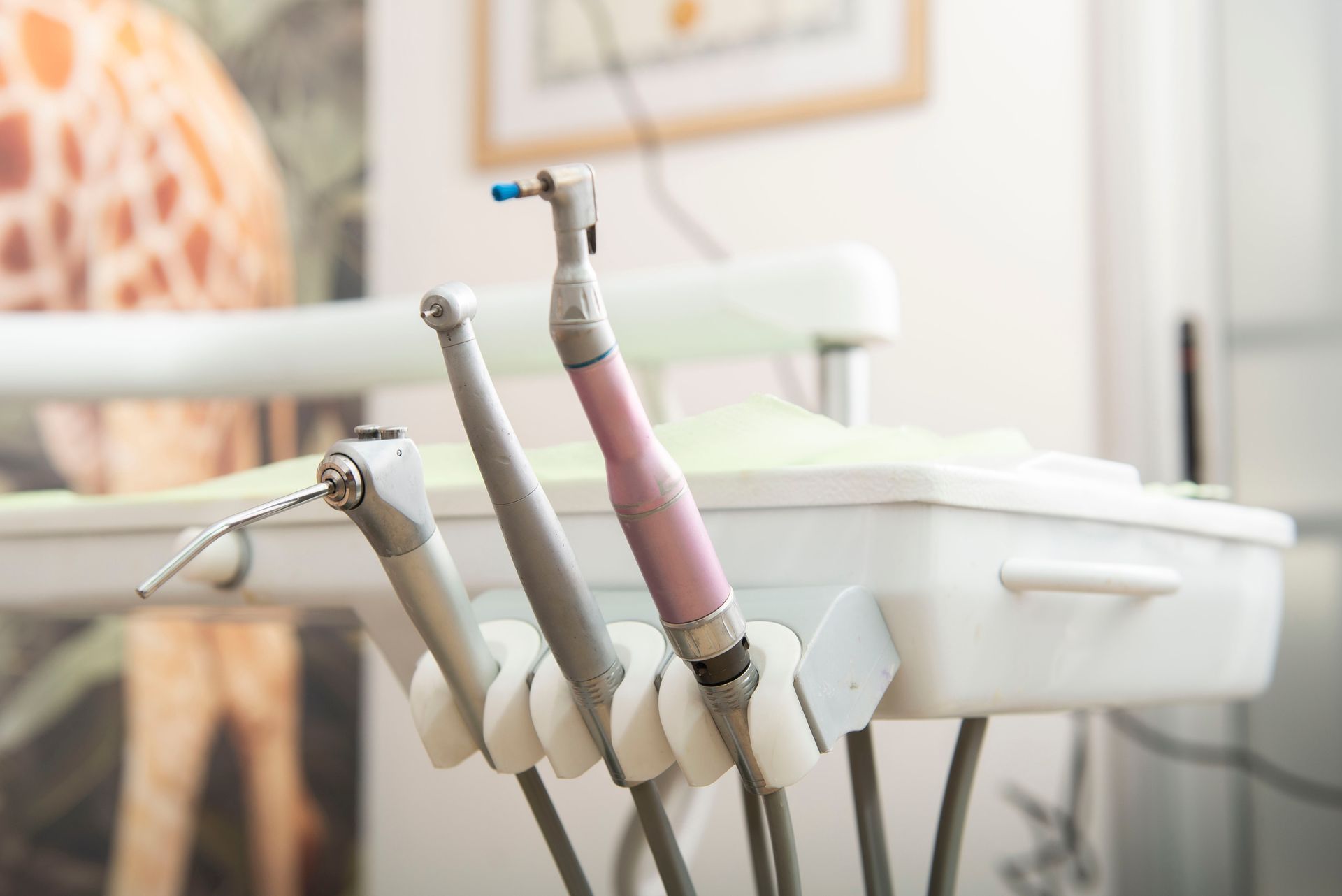 Dental tools in a clinic, including pink and gray handheld instruments near a treatment chair