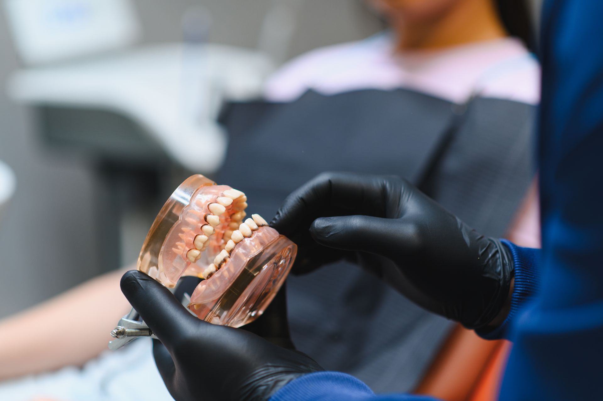 Gloved hands holding a clear dental aligner in a clinic setting