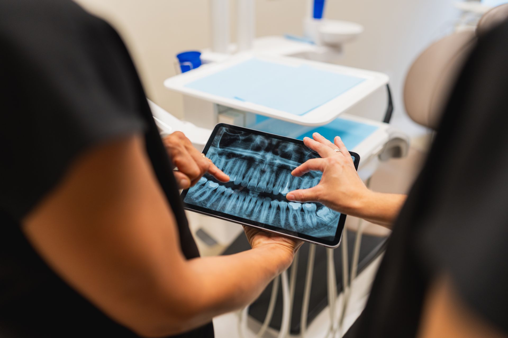 Dentist and assistant reviewing dental X-rays on a tablet in a clinic