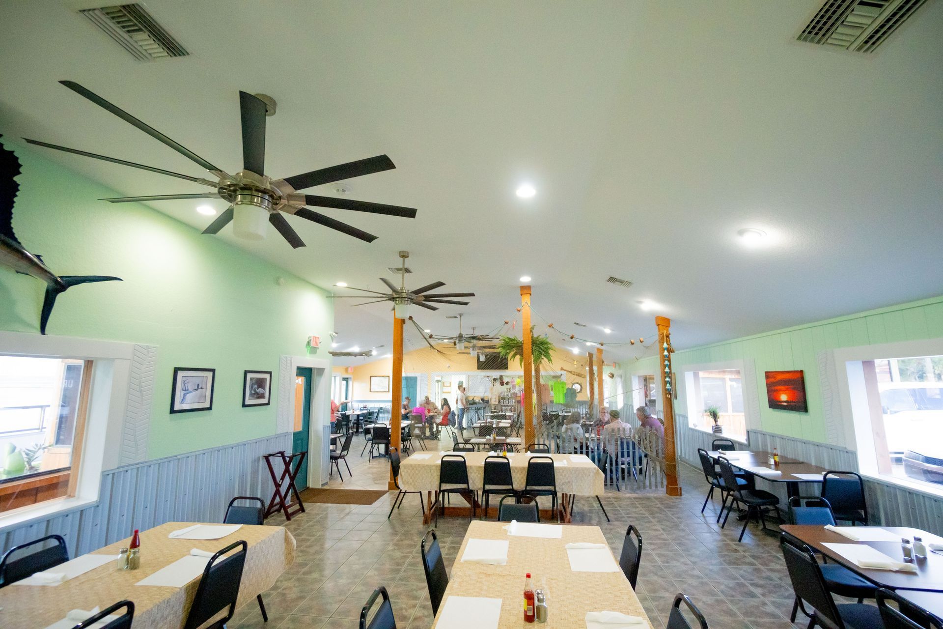 A large dining room with tables and chairs and a ceiling fan.