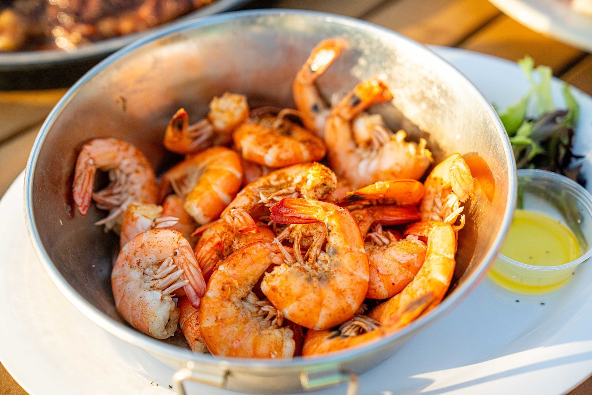 A bowl of shrimp is sitting on a white plate on a table.