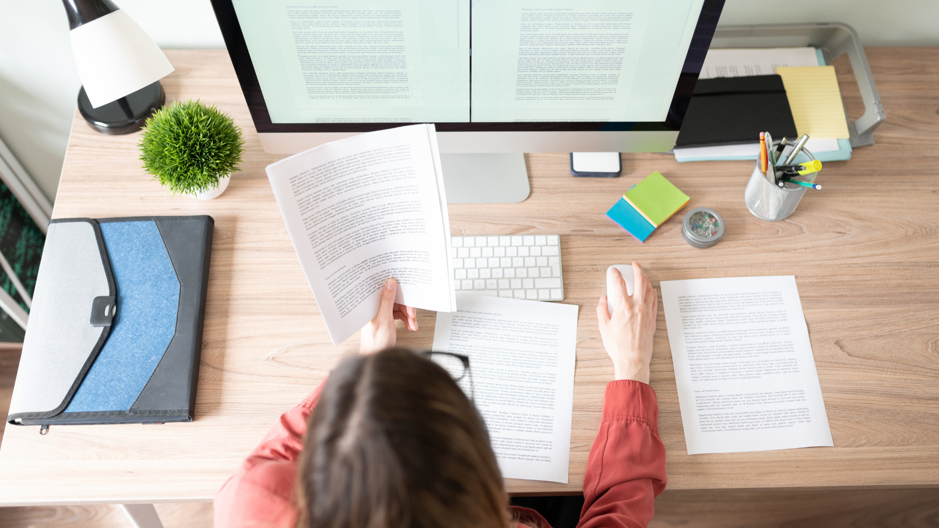 A woman is sitting at a desk with a computer and papers