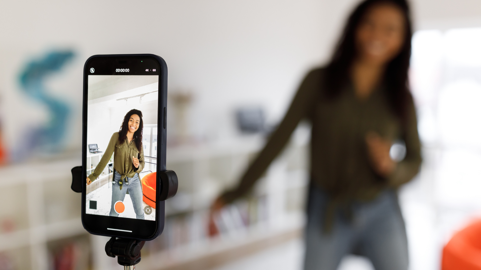 A woman is performing in front of a cell phone on a tripod