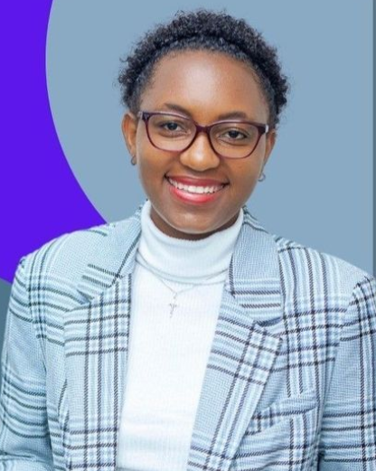 Portrait of a smiling person in glasses, wearing a plaid blazer over a white turtleneck, against a blue background.