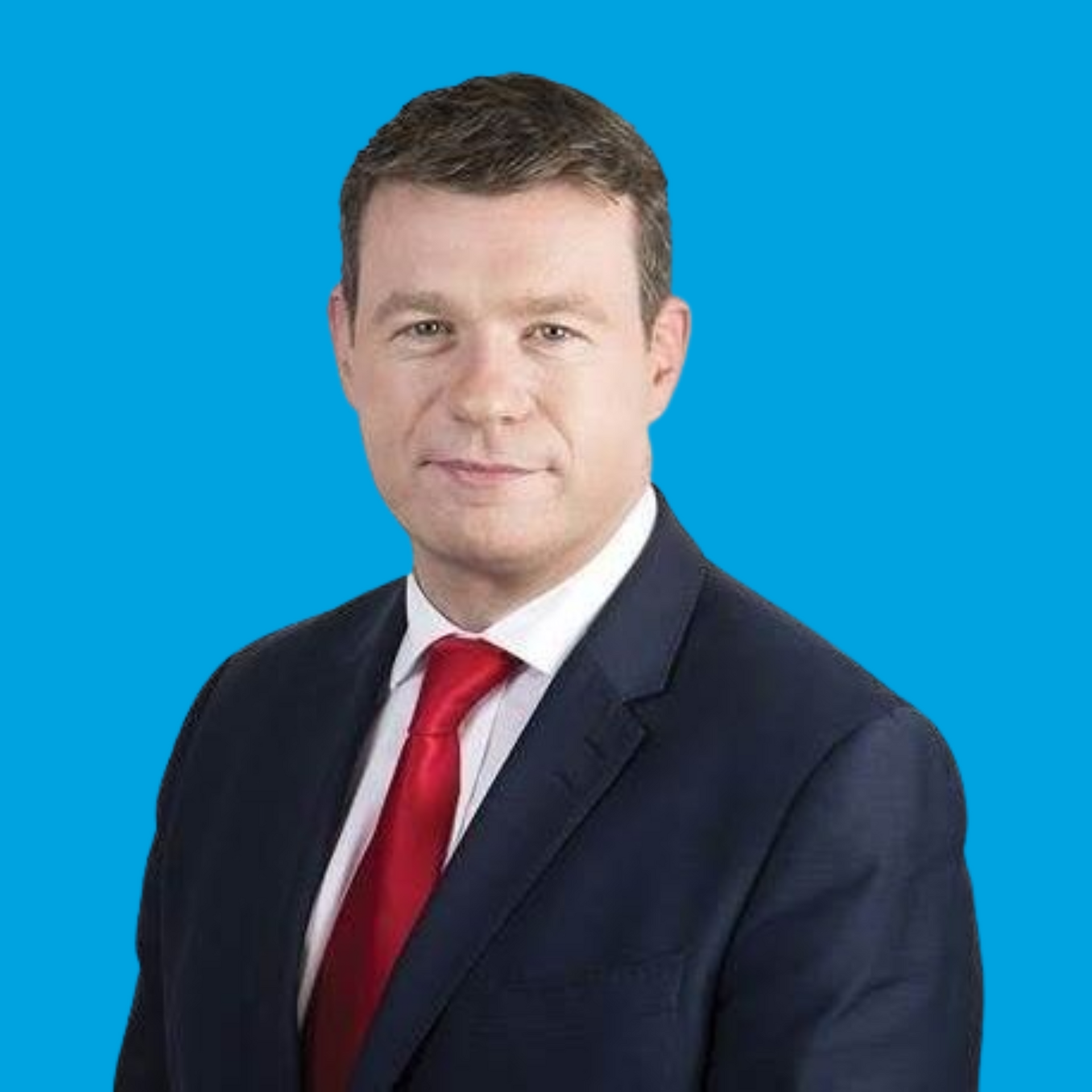 Portrait of a man in a dark suit and red tie against a blue background