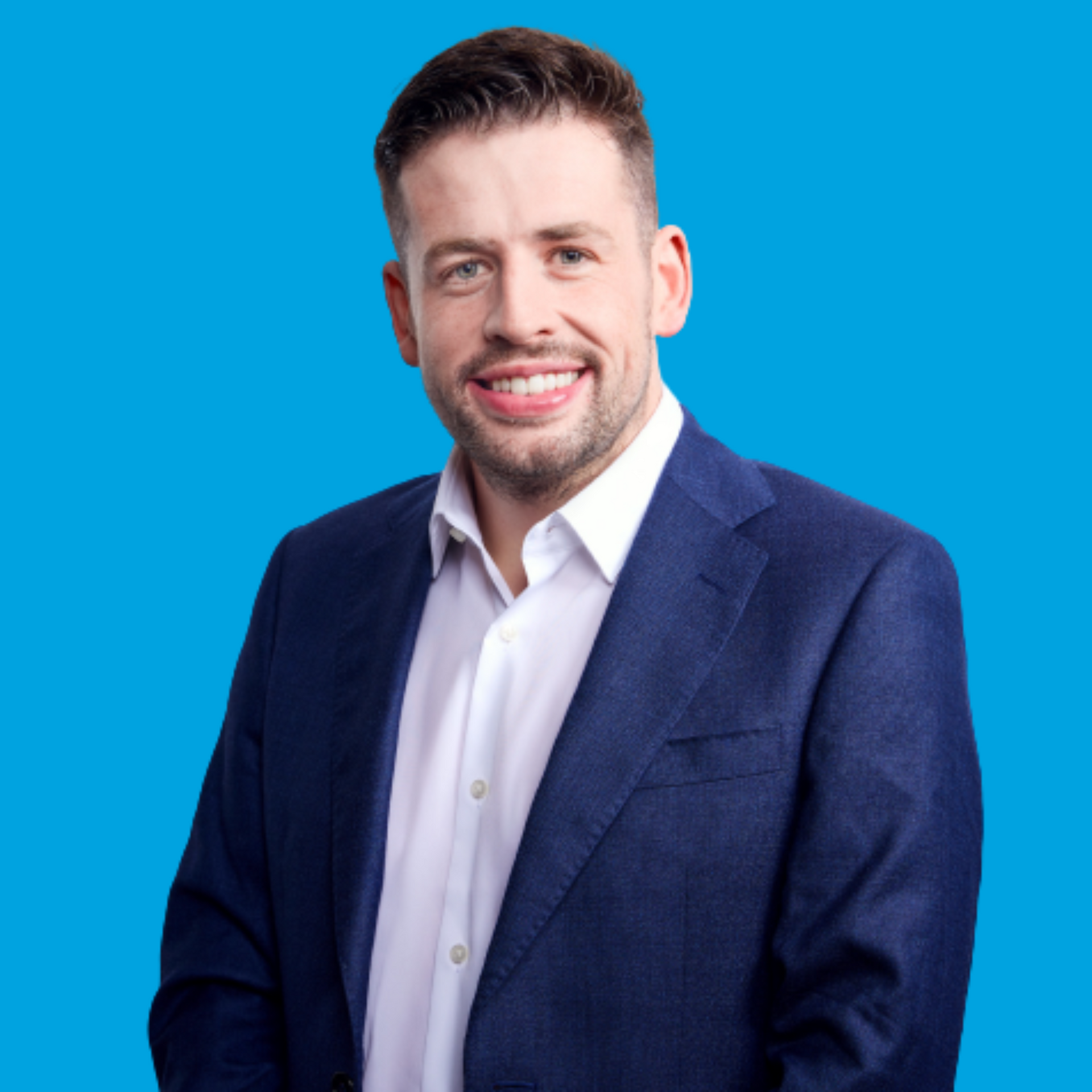 Smiling man in a navy blazer and white shirt against a blue background