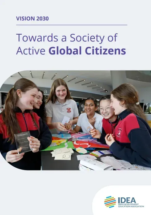 Students around a table with colorful paper flags, under the text “Towards a Society of Active Global Citizens.”