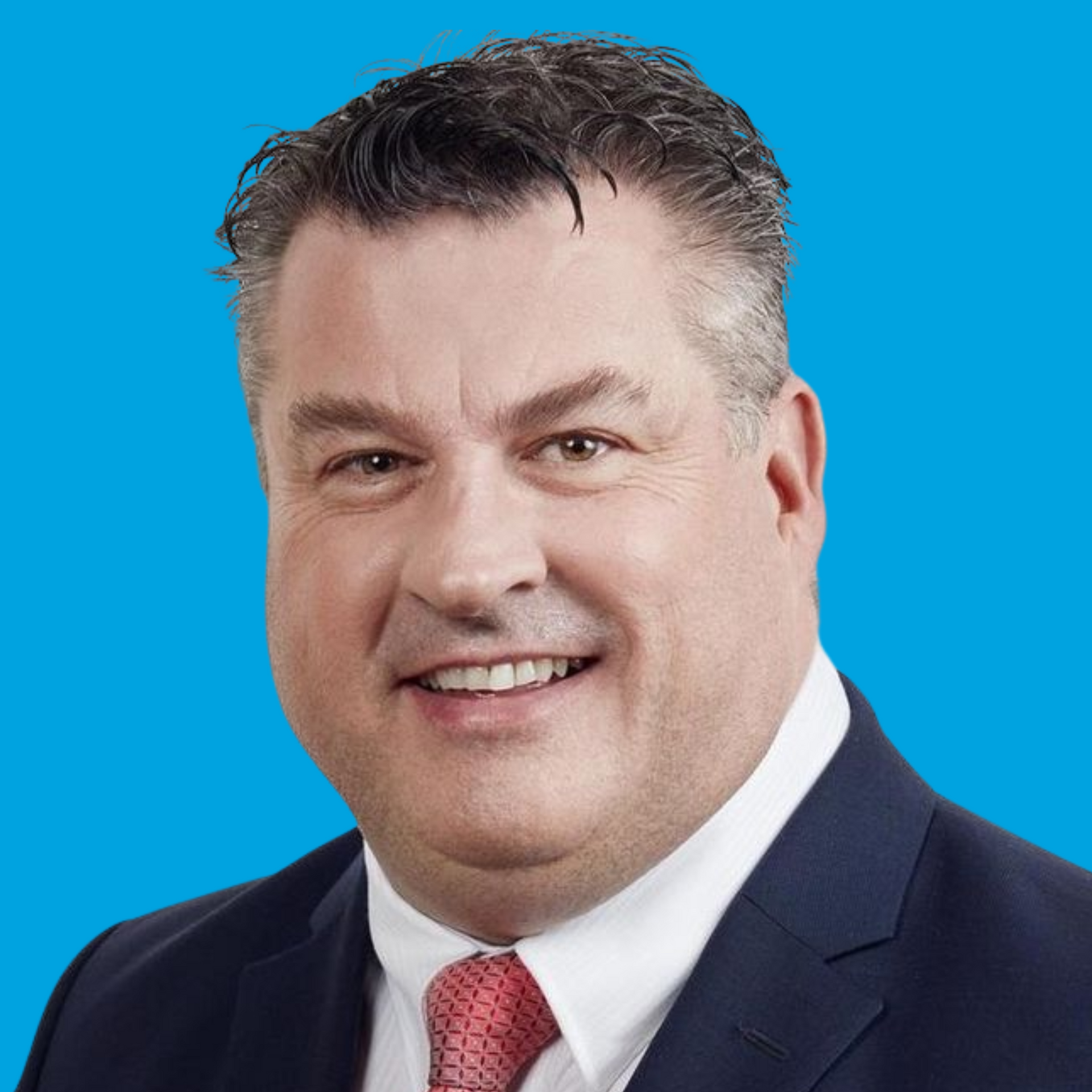 Smiling man in a navy suit and red tie against a blue background