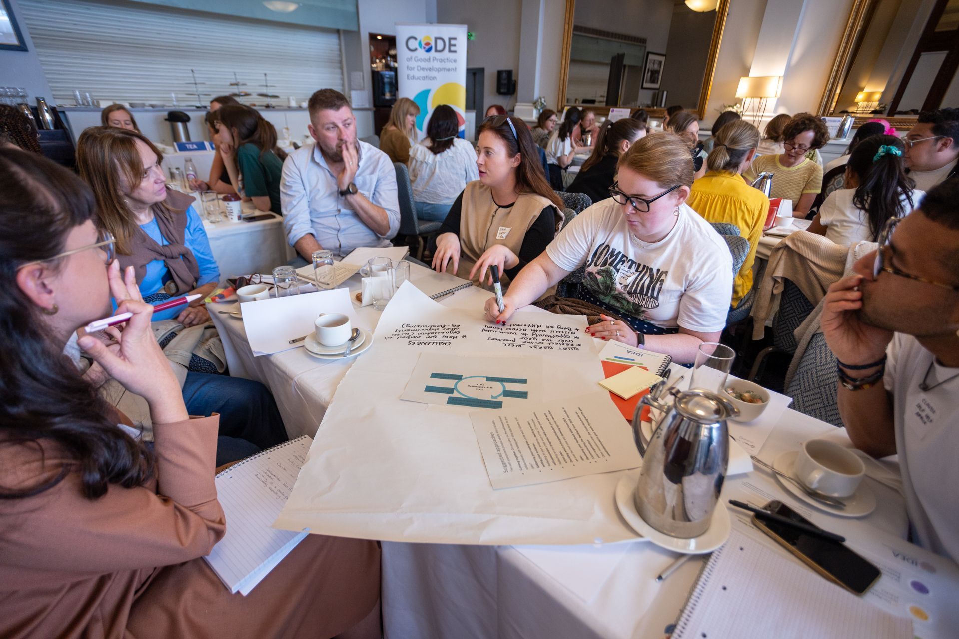 People gathered around a table playing a card game at an indoor event.