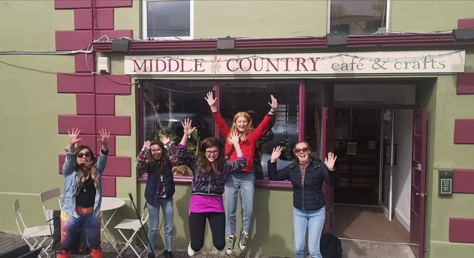 Group posing and cheering outside Middle Country Cafe & Crafts storefront