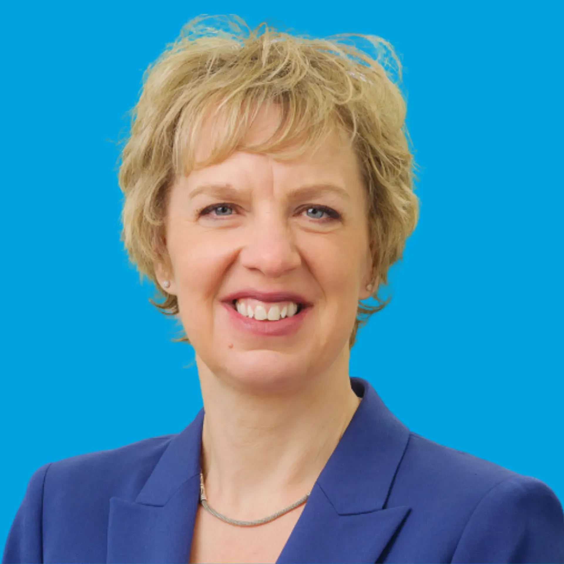 Portrait of a smiling person in a blue blazer against a bright blue background