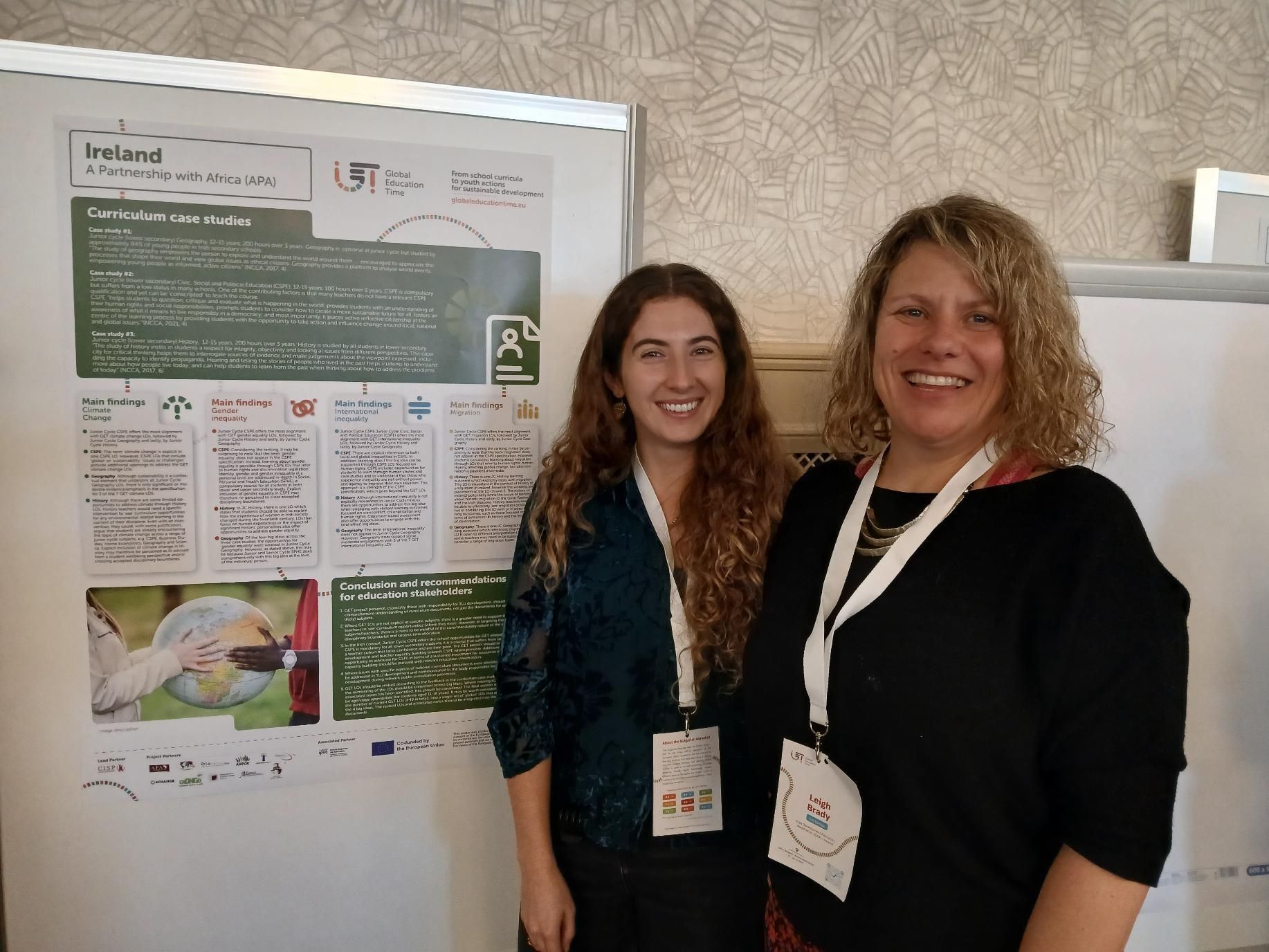 Two women posing beside a poster presentation board at a conference