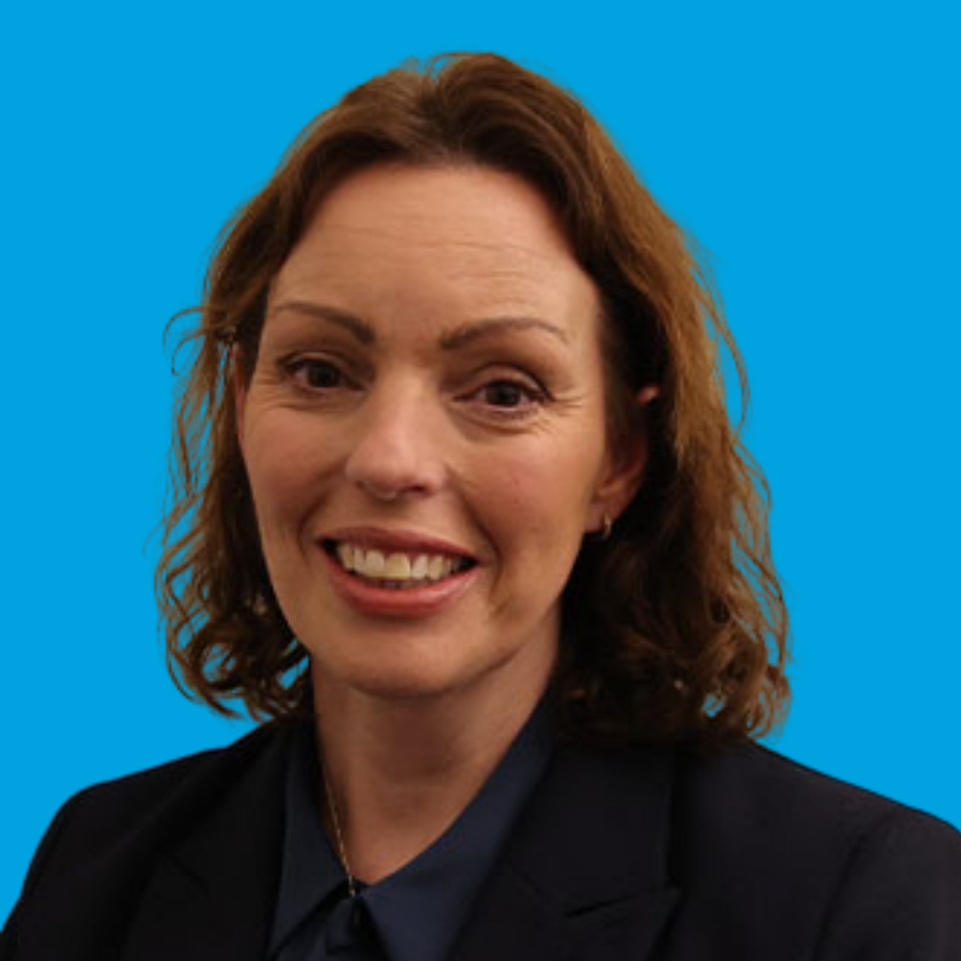 Portrait of a smiling woman in a dark blazer against a bright blue background