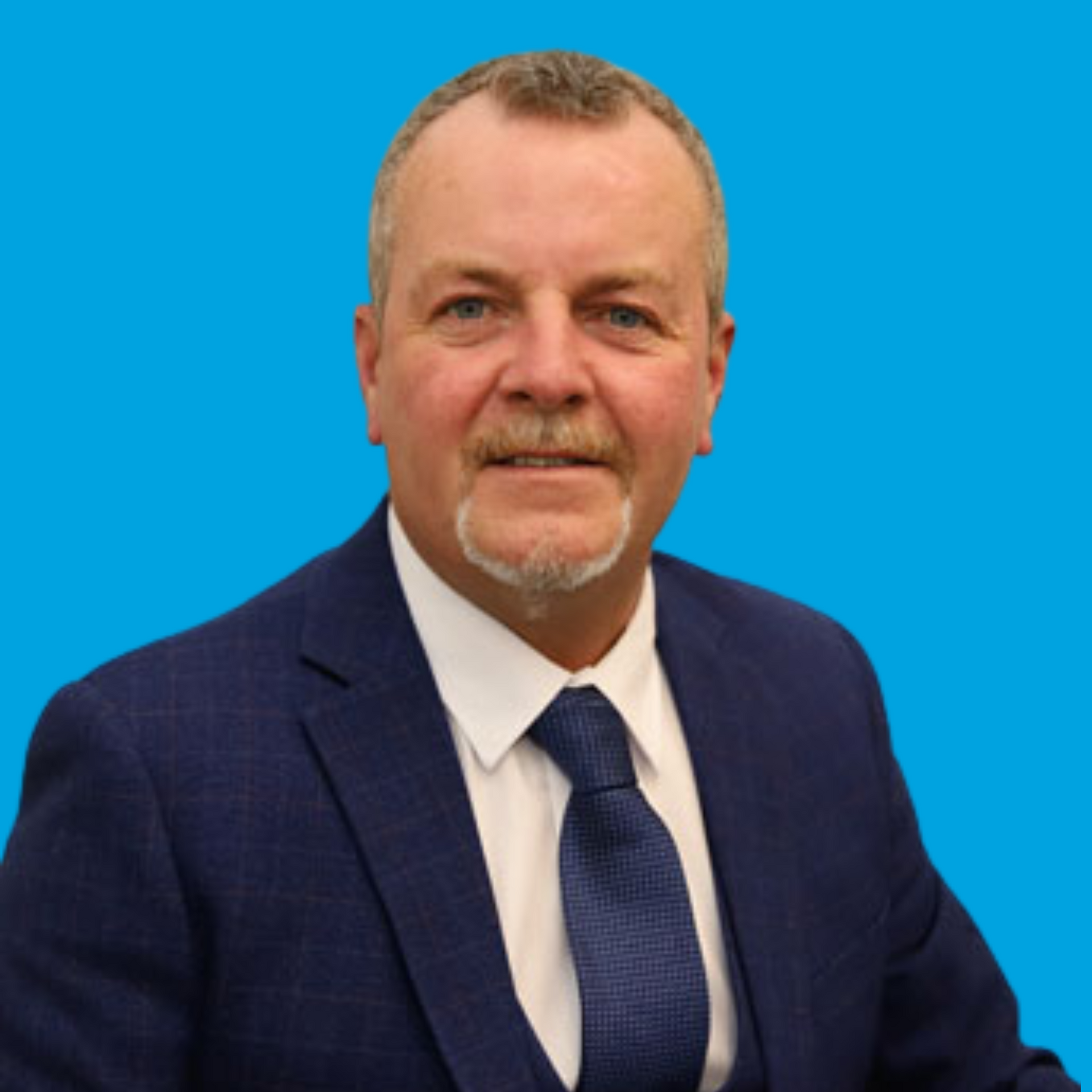 Man in a navy suit and tie smiling against a bright blue background