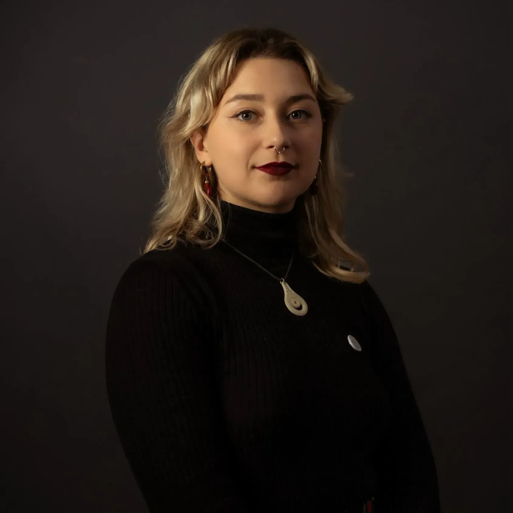 Portrait of a woman in a black turtleneck against a dark background